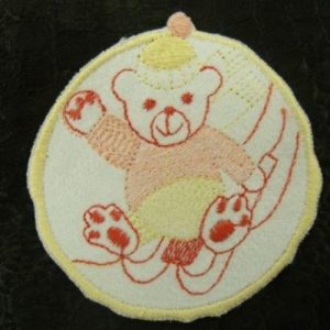 écusson thermocollant motif NOUNOURS SUR LUGE rose jaune et rouge sur fond blanc 6.5 cm